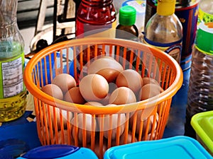 Fresh Raw Chicken Eggs in Orange Plastic Basket in Kitchen