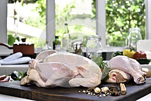 Fresh raw chicken with ingredients for cooking on a wooden cutting board in the kitchen