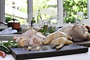 Fresh raw chicken with ingredients for cooking on a wooden cutting board in the kitchen