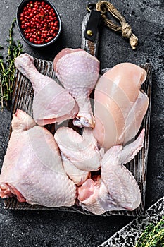 Fresh raw chicken meat, wings, breast, thigh and drumsticks. Black background. Top view