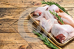 Fresh raw chicken meat, wings, breast, thigh and drumsticks on a wooden tray. Wooden background. Top view. Copy space