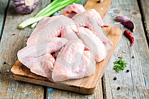 Fresh raw chicken wings with garlic, onion and peppers on a cutting board