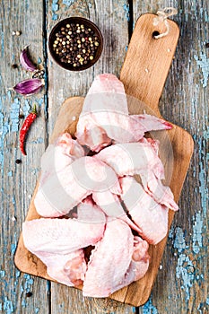 Fresh raw chicken wings with garlic and peppers on a cutting board