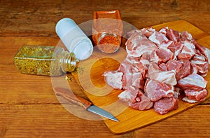 Fresh raw chopped beef on a wooden cutting board with spices, herbs and vegetables.