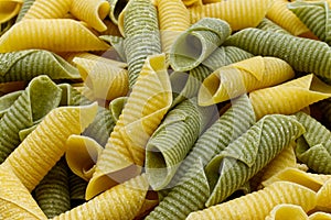 Fresh raw colored pasta. Italian Maccheroni al pettine on wooden table. Close-up background