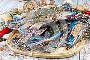 Fresh Raw Crab surrounded by spices and ingredients on a wooden table