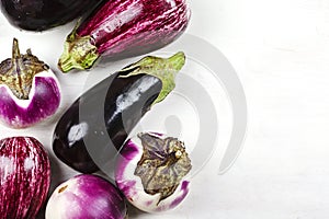 Fresh raw eggplants of different color and variety on a white background
