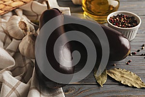 Fresh raw eggplants and spices on wooden background