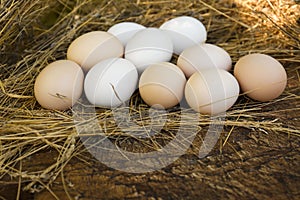 Fresh raw eggs and straw on wooden surface