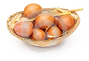 Fresh and raw eggs in wicker basket and straw.