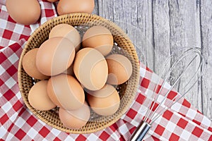 The Fresh raw eggs in the wooden basket and tablecloth on wooden table