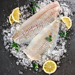 Fresh raw fillet white fish Pangasius with spices on ice over dark stone background.  Seafood, top view, flat lay, copy space