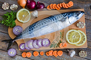 Fresh raw fish mackerel and ingredients for cooking on a wooden background