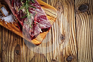 Fresh raw flank steak on the very nice rustikal wooden plate. Old wooden background with copy space for text