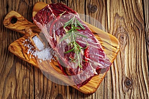 Fresh raw flank steak on the very nice rustikal wooden plate. Old wooden background with copy space for text