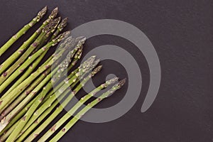 Fresh raw green asparagus spears on black background, copy space