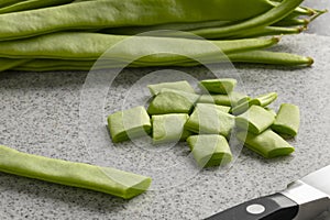 Fresh raw green flat beans and slices on a cutting board close up