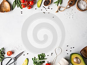 Fresh raw greens, vegetables, spices and kitchenwere frame on grey background. top view photo