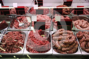 Fresh raw ground meat and sausages in refrigerator at market