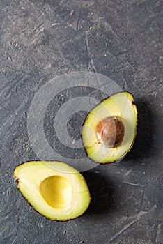 Fresh raw halfs of avocado on a dark stone table, healthy eating concept, top view with copy space