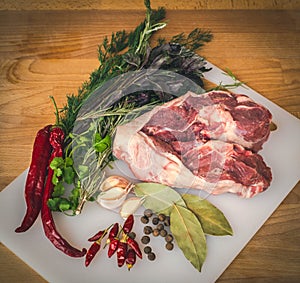 Fresh raw lamb on wooden cutting board, spices and herbs. Whole uncooked lamb prepare for cooking.