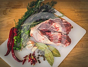 Fresh raw lamb on wooden cutting board, spices and herbs. Whole uncooked lamb prepare for cooking.