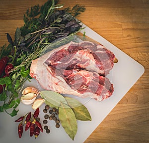 Fresh raw lamb on wooden cutting board, spices and herbs. Whole uncooked lamb prepare for cooking.