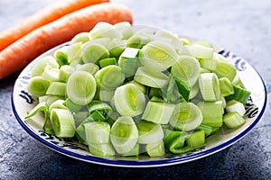 Fresh raw leek slice in a bowl with carrots. washed sliced ready-to-cook leeks