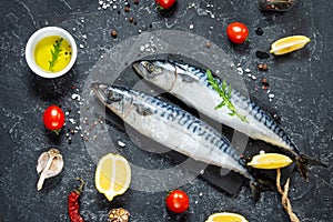 Fresh raw mackerel with lemon and spices on a black stone background