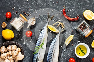 Fresh raw mackerel with lemon and spices on a black stone background