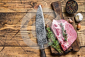Fresh Raw marble meat pork steaks on a cutting board with knife. wooden background. Top view. Copy space