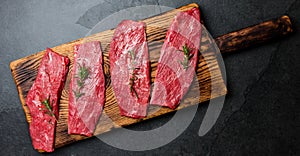 Fresh raw meat beef steaks. Beef tenderloin on wooden board, spices, herbs, oil on slate gray background. Food cooking