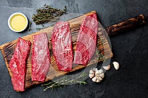 Fresh raw meat beef steaks. Beef tenderloin on wooden board, spices, herbs, oil on slate gray background. Food cooking background