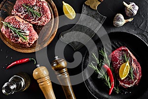 Fresh raw meat. Beef Tenderloin and marbled beef steaks on grill pan and frying board with seasoning, black background