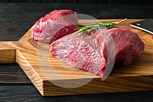 Fresh raw meat on chopping board with rosemary