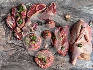 Fresh raw meat. Different types of raw pork meat, chicken, beef, turkey giblets with herbs on dark marble, copy space