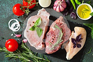 Fresh raw meat. Different types of raw pork meat, chicken fillet and beef with vegetables and herbs