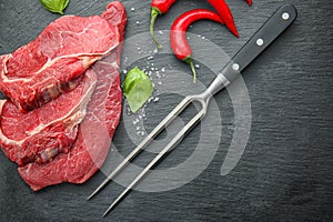 Fresh raw meat with fork and fresh spices on slate plate