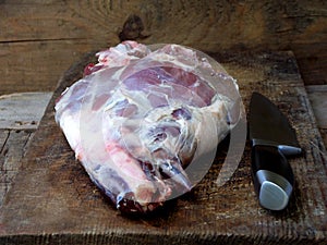 Fresh and raw meat. Leg of lamb with a knife for roasting, stewing, pilaf, barbecue, kebab, shurpa