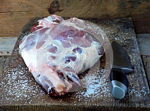 Fresh and raw meat. Leg of lamb on a wooden board with a knife for roasting, stewing, pilaf, barbecue, kebab, shurpa