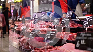 Fresh raw meat with price tags on the showcase in the store with sellers