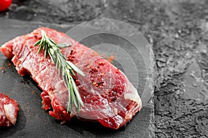 Fresh raw meat with rosemary on slate plate