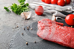 Fresh raw meat with spices and tomatoes on slate plate