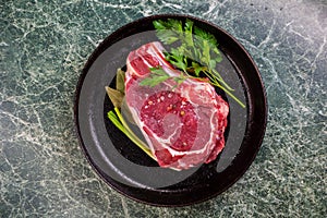 Fresh Raw Meat for Steak Ribeye, Decorated with Herbs and Sprinkled with Spices and Coarse Salt, Lies in a Cast-Iron Vintage Pan.