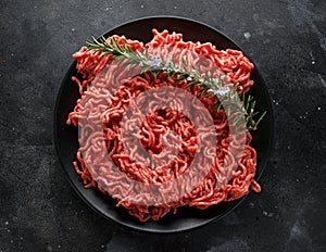 Fresh Raw mince, Minced beef, ground meat with herbs and spices on black plate