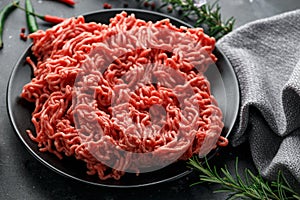 Fresh Raw mince, Minced beef, ground meat with herbs and spices on black plate