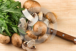 Fresh raw mushrooms brown mushrooms and green arugula on a wooden background. Shiitake Selective focus