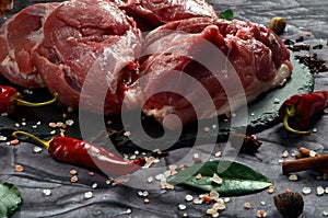 Fresh raw mutton shoulder meat isolated on black stone background with spices