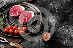 Fresh raw organic beef steak, on black dark stone table background, with copy space for text