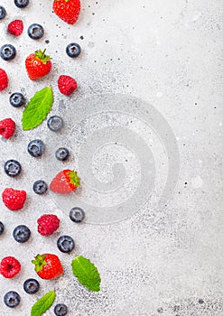 Fresh raw organic berries on kitchen table background. Space for text. Top view. Strawberry, Raspberry, Blueberry and Mint leaf